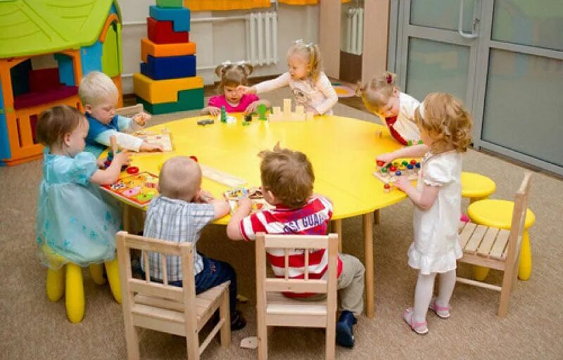 Детские ясли. Занятия в яслях детского сада. Дети сидят за столом в детском саду. Подготовка ребенка к детскому дошкольному учреждению. Детский сад за столом.