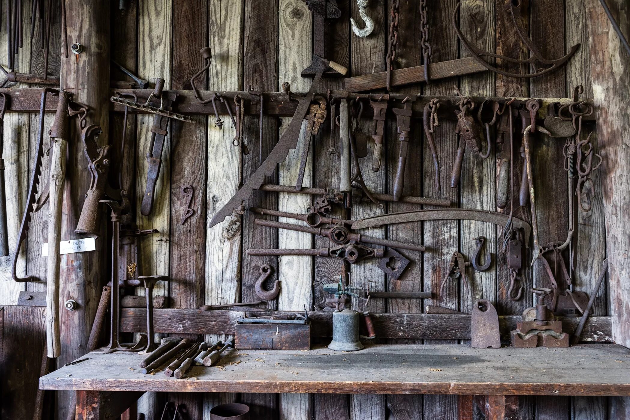 Среди деревьев кузнецы. Старинные инструменты. Старинная кузница. Старинный кузнечный инструмент. Старинная мастерская.