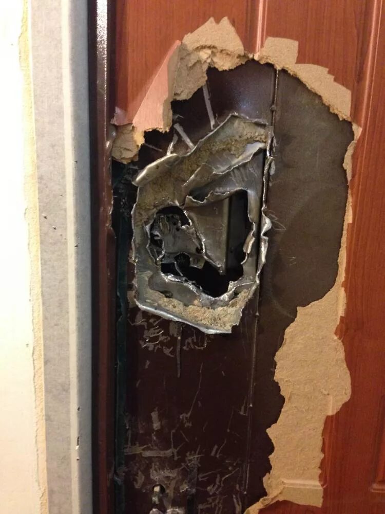 Выбили дверь в квартиру. Поврежденная входная дверь. Сломанные двери металлические входные. Поврежденный дверной замок. Сломанная железная дверь.