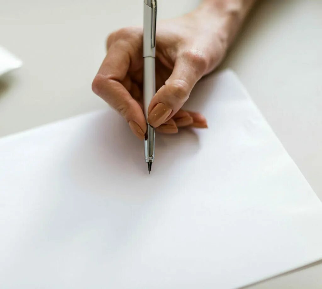 Человек пишет на листе бумаги. Ручка и бумага. Лист и ручка. Чистый лист с ручкой. Лист бумаги на столе.