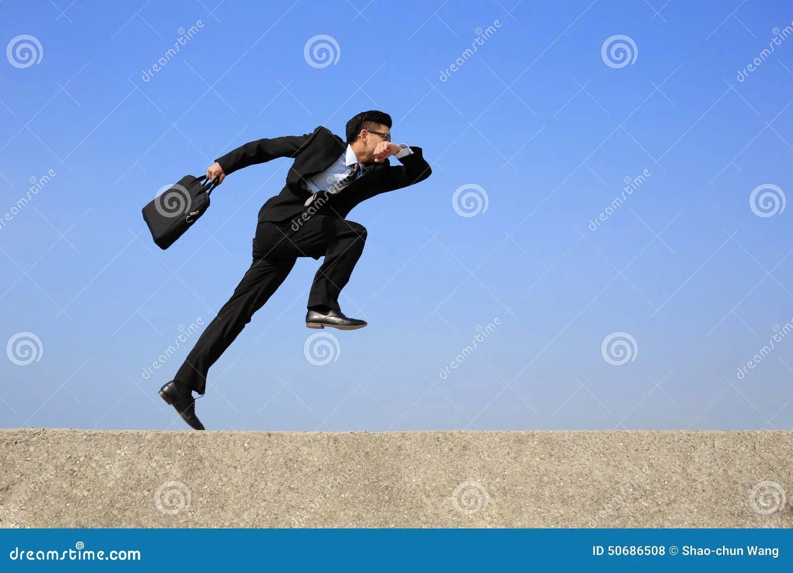 Человек в костюме прыгает. Мужчина в костюме бежит. Деловой человек бежит. Выпрыгивающий человек на бегу.