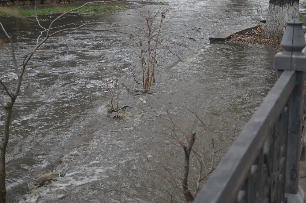 Поток воды переливается через дорогу