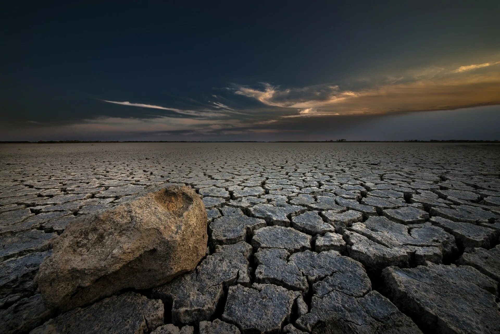 Трещины озера. Сухая земля. Каменистая почва. Каменная пустыня. Потрескавшаяся земля в пустыне.