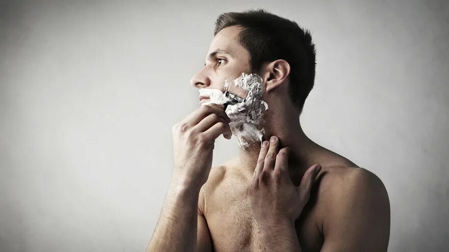 Ухоженный мужчина. Мужчина бреется станком. Мужчина бреется в одежде. Бритья для мужчин. Он брит.