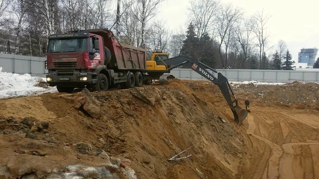 разработка грунта вывозом. разработка грунта вывозом. рытье котлована. разработка грунта вывозом. экскаватор копает песок камаз.