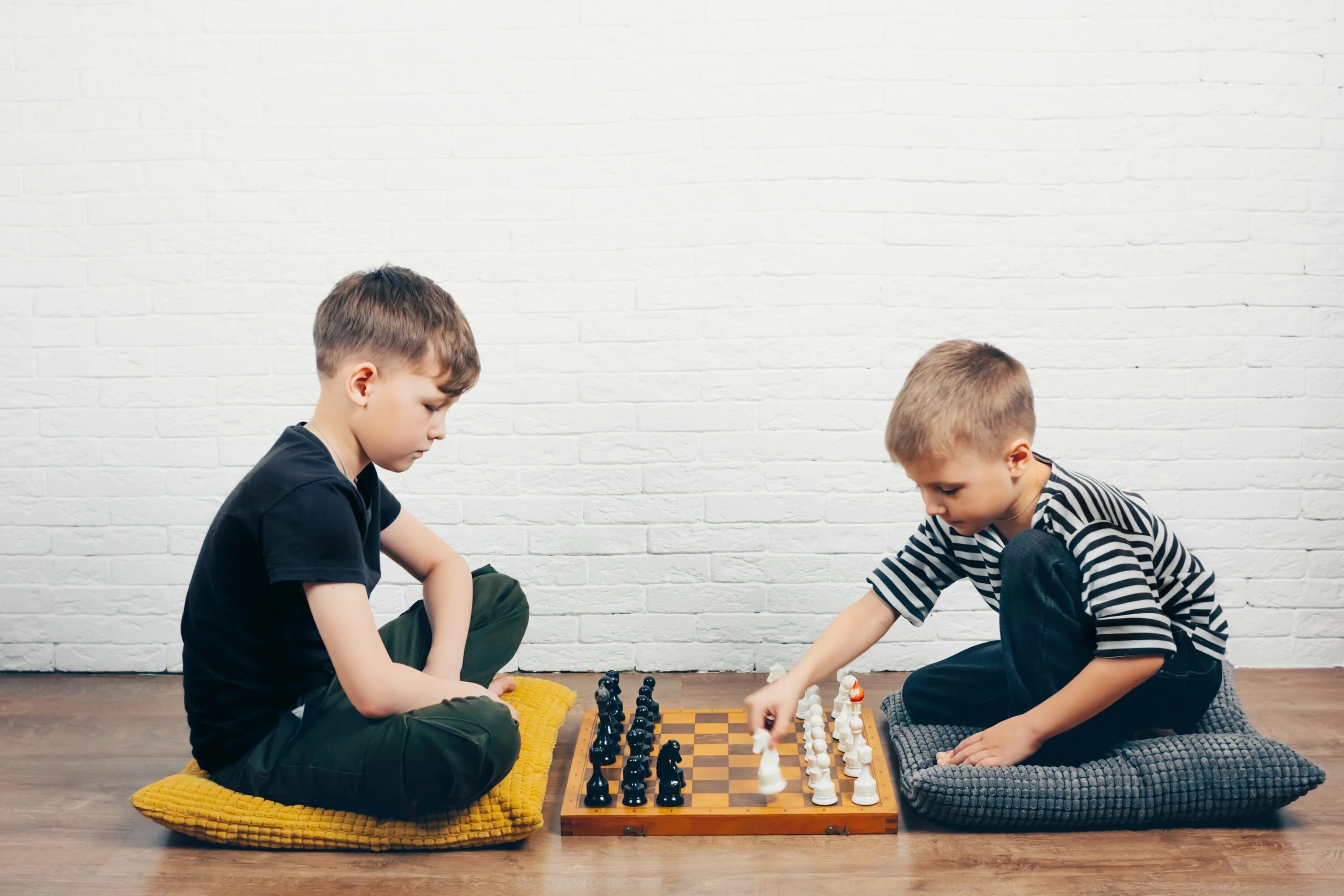 Мальчик играет на полу. Два мальчика играют в шахматы. Дети играют в шахматы. Два парня играют в шахматы.