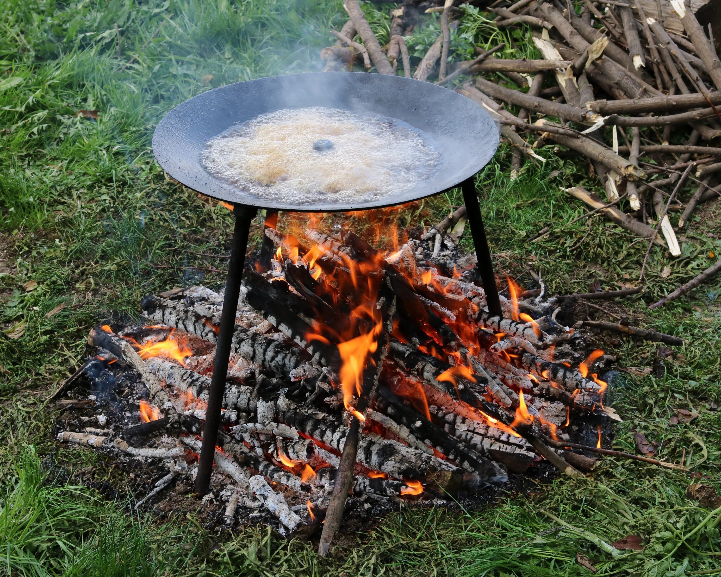 Low on fire. Cooking on fire. cook on fire. people campfire cooking.