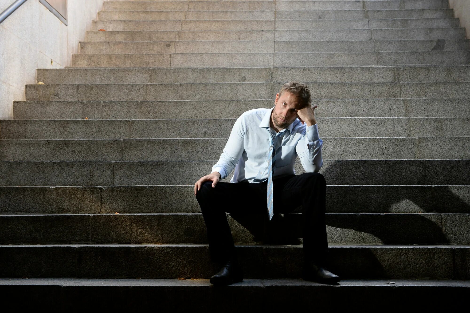 Мужчина сидит на ступеньках. Парень сидит на лестнице. Человек на ступеньках. Мужчина на лестнице. Человек сидит на ступеньках.