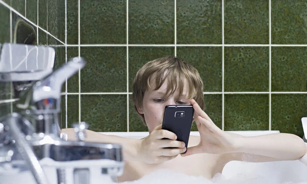 Телефон в ванной. Человек в ванне с телефоном. Смартфон в ванне. Зарядка смартфона в ванной.