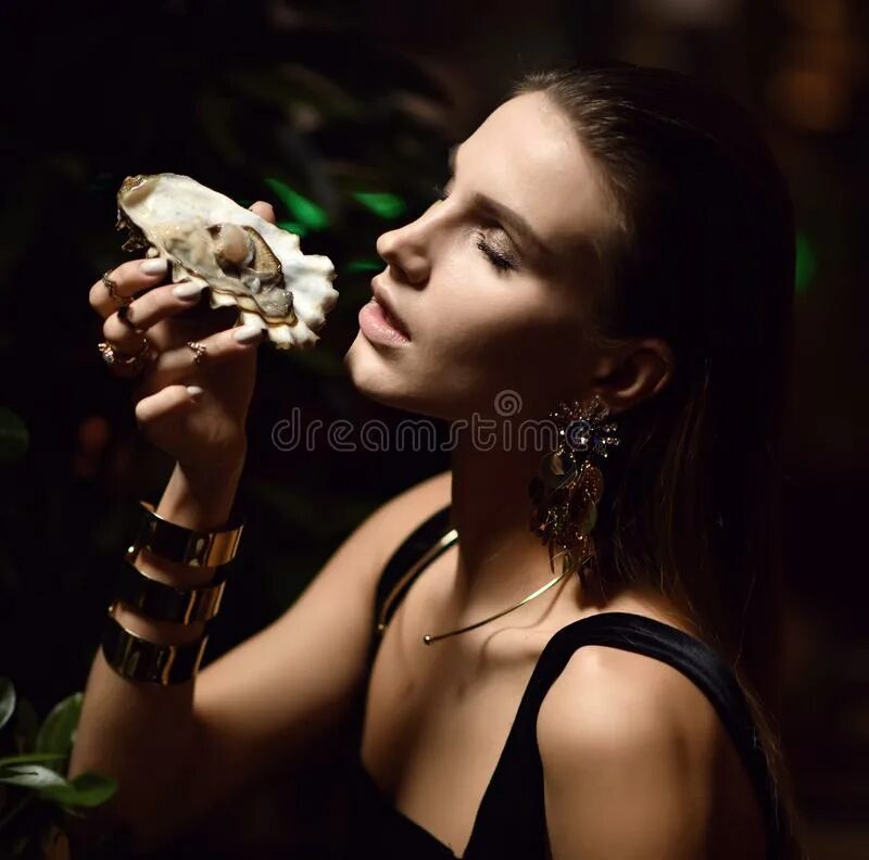 Девушка с устрицами. Устрица в руке. Девушка есть устрицы. Девушка ест устрицы в ресторане. Девушка пробует устрицы.