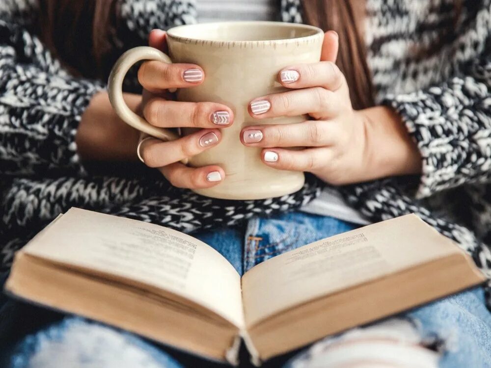 Читать книгу кофе. Кружка рука. уютное чтение. чтение и кофе. чашка чая в руках.