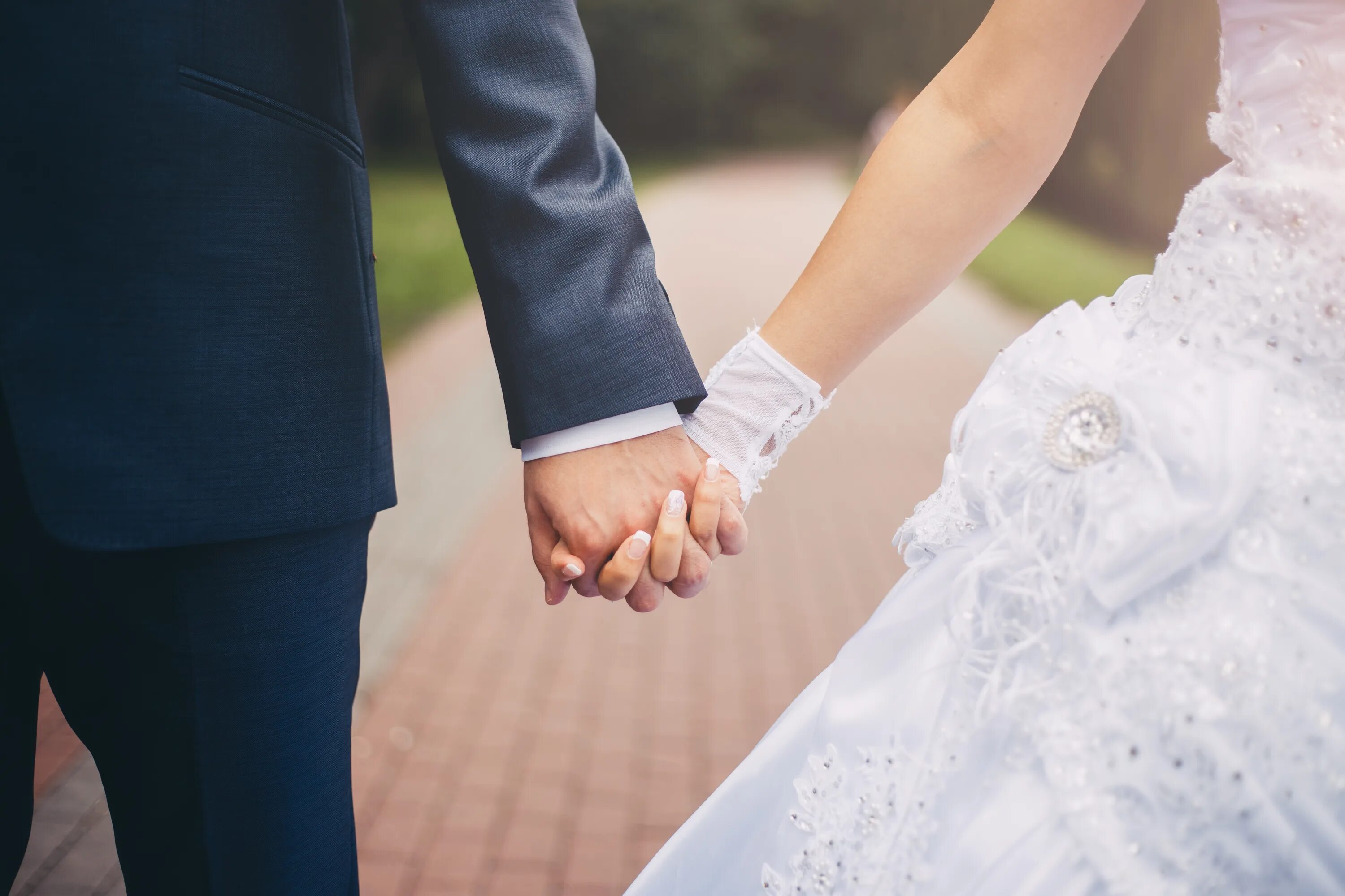 Жених и невеста держатся за руки. Брак свадьба. Невеста на руках у жениха. Молодожены.