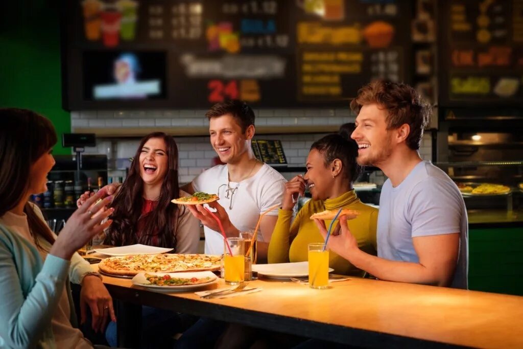 Люди в пиццерии. Люди в кафе с пиццей. Друзья в кафе едят пиццу. Друзья в кафе с пиццей.