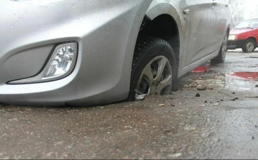 Колесо в яме на дороге. Попал в яму. Повреждение автомобиля. Попадание колеса в яму. Машина попала в яму на дороге.