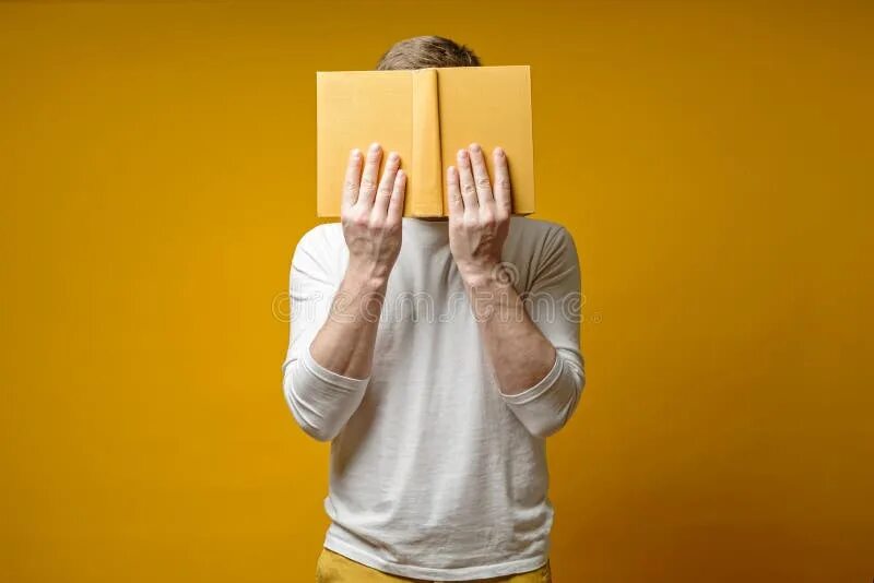 Лицо закрытое книгой. Закрыл лицо книгой. человек закрывает лицо книгой. парень закрыл лицо книгой.