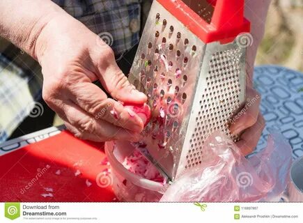 Женщина трет овощи на терке Стоковое Изображение - изображение насчитывающей ред