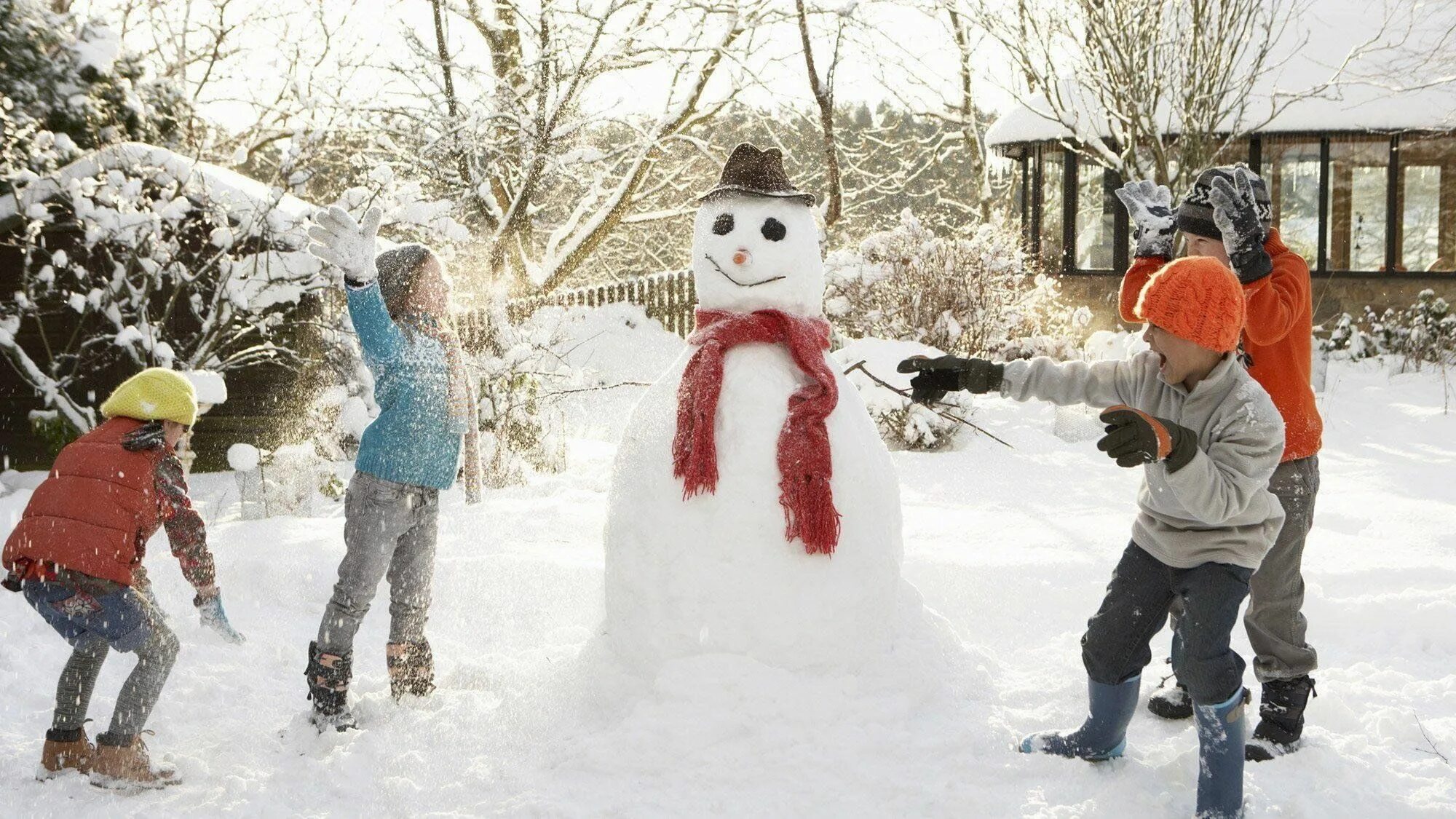 Лепить снеговика зимой. Зимние развлечения. Снежные забавы. Дети лепят снеговика. Снежные забавы для детей.