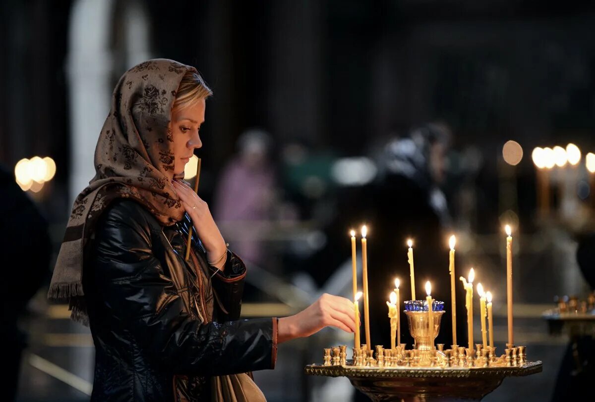 Мужчина ставит свечу. Девушка в храме. Женщина молится в храме. Девушка молится в церкви. Православная девушка.