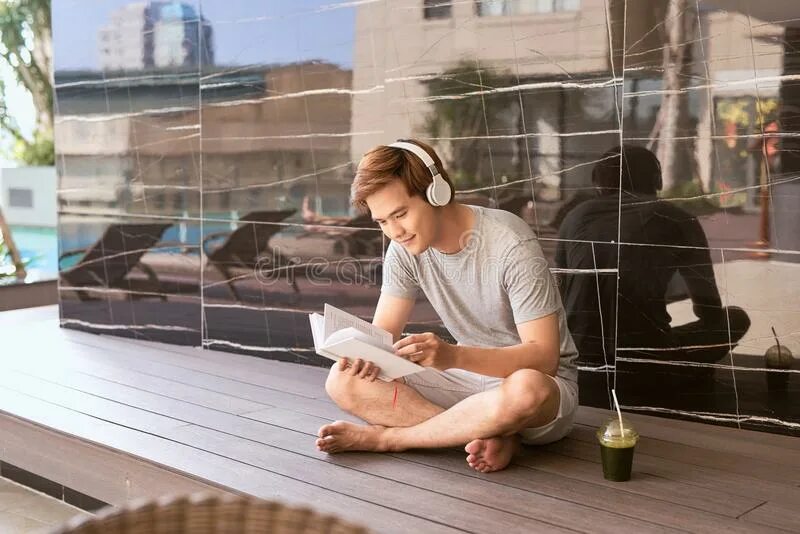 Listening to Music and reading. Listen to Music and reading a book. Парень читает на полу боком. Мужчина читает книгу сидя на фоне своего дома в саду фото. Listen to music read a book