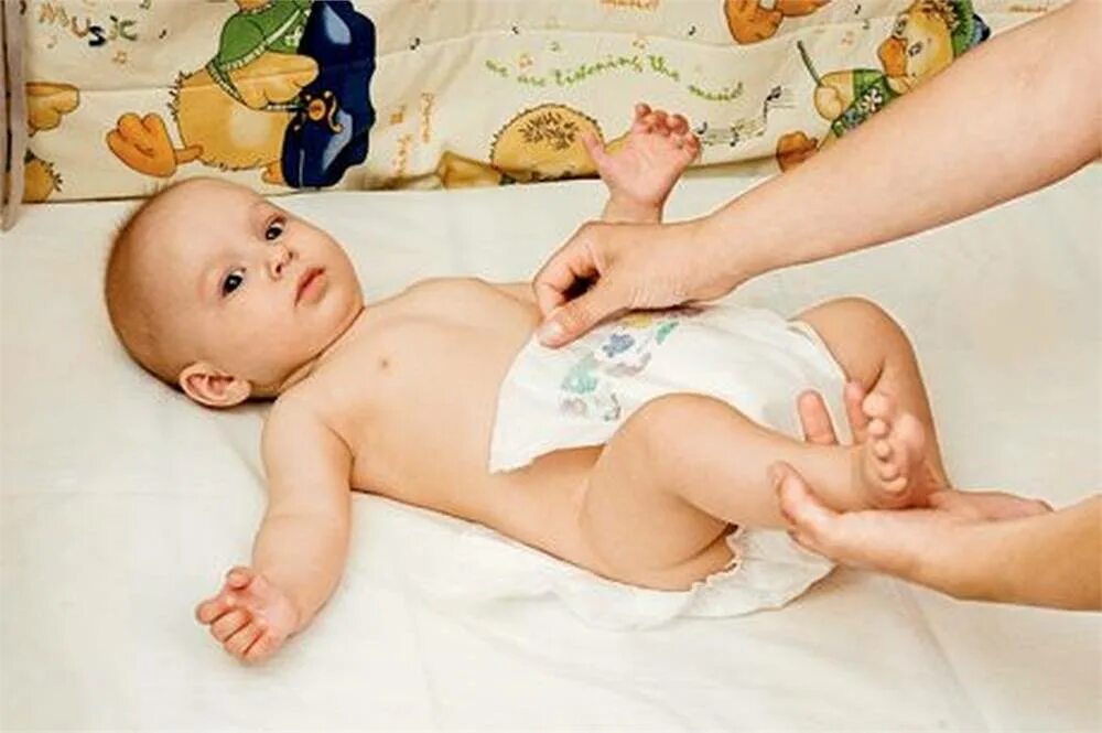Ребенку меняют подгузник. Одевание памперса грудничку. Новорожденный в подгузнике.