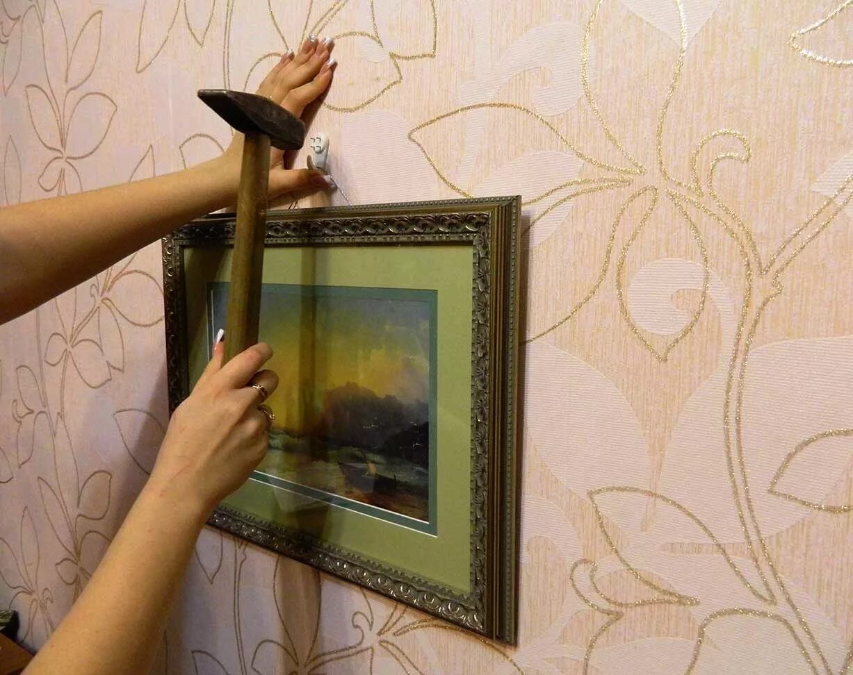 Как крепятся картины. Повесить картину на стену. На что вешать картины на стену. Вешает картину. На что приклеить картину к стене.