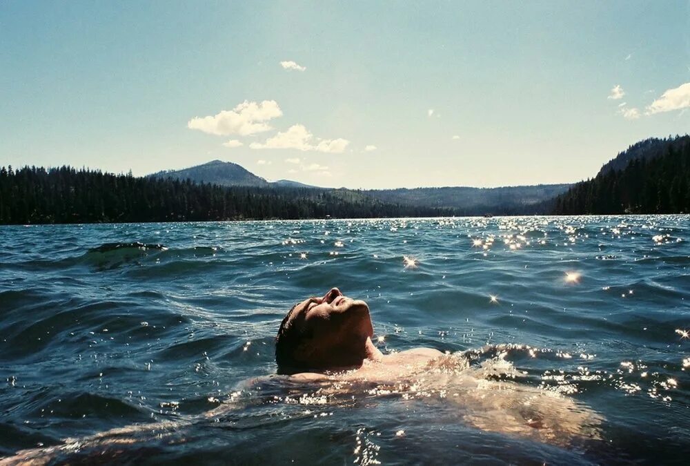 Парни на озере. Мужчина лежит в воде. Парень лежит в воде. Парень плывет на спине.