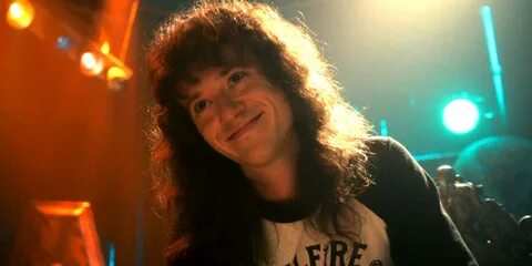 Eddie Munson Smiling Under Blue and Orange Lighting Wallpaper. 