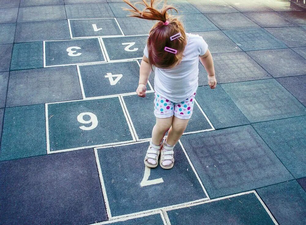 Дети прыгают в классики. Дети играют в классики. Девочка играет в классики. Девочки скачут в классики. Девочка играет в классики.