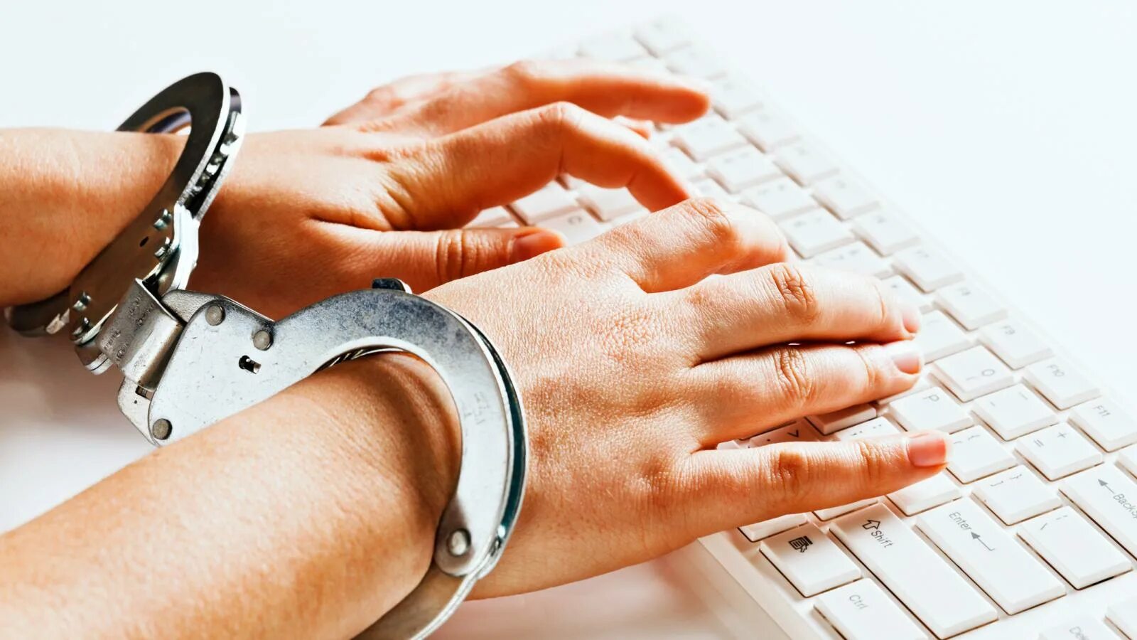 Наручники на клавиатуре. Ноутбук и наручники. В наручниках за компьютером. Руки в наручниках.