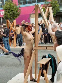 nude woman chained to a post is being whipped.