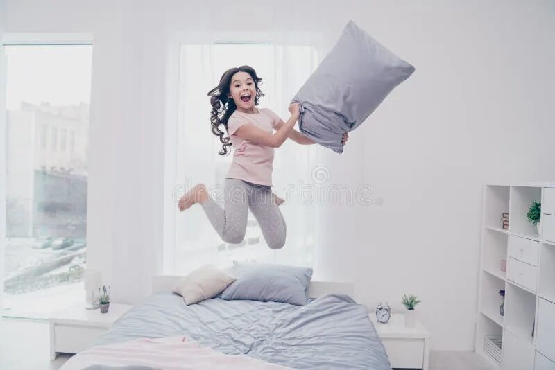 Подруги прыгают на кровати. Девушка прыгает в пижаме. Девушка верхом на подушке. Подушка для прыжков. Пара прыгает в постель.