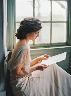 a woman sitting on a window sill reading a book 