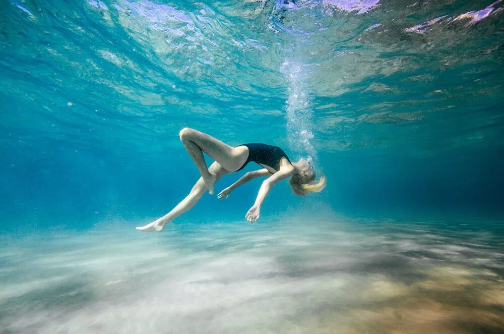 Девушка плавает в море. Подводная фотосессия. Девушка плывет в море. Под водой.