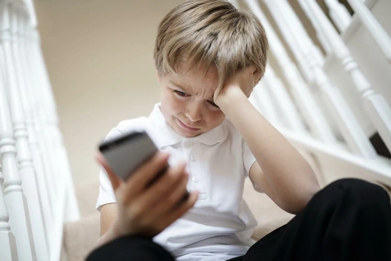 Ребенку угрожают в школе. Ребенок с телефоном. Подросток с телефоном. Агрессия в интернете. Грустный ребенок с телефоном.