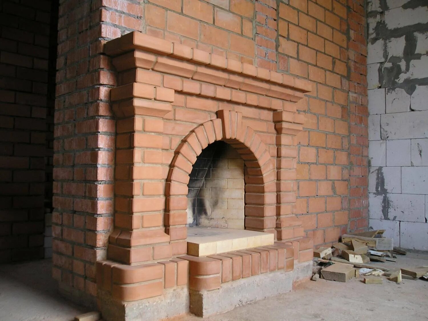 Угловой камин из кирпича в гараже. Арочный камин из кирпича. Портал из кирпича фото. Фигурный кирпич для кладки печей. Камин портал из кирпича.