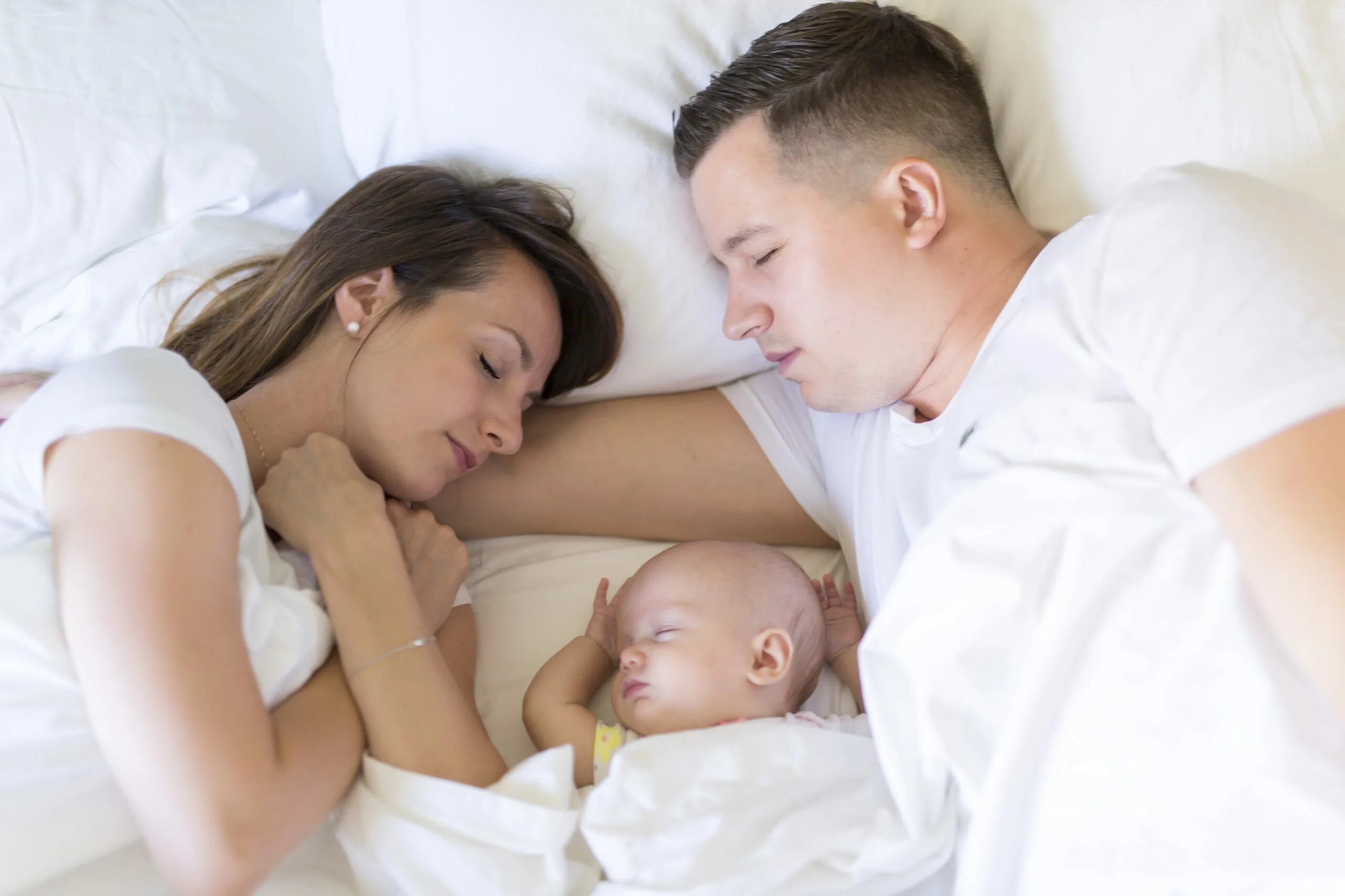 Молодая мама в постели. Позы для совместного сна с новорожденным. Совместный сон ребенка с родителями. Позы для совместного сна с грудничком. Ребенок в кровати с родителями.
