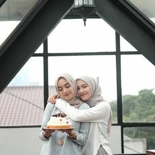 two women standing next to each other holding a cake 