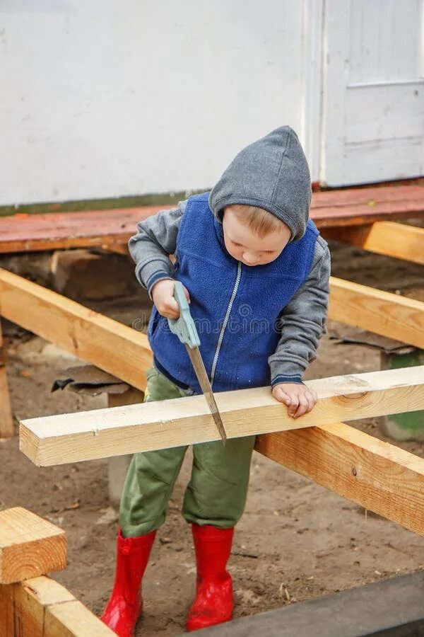 мальчик пилит. ребенок пилит. мальчик пилит дерево. папа учит ребенка. пилить дрова.
