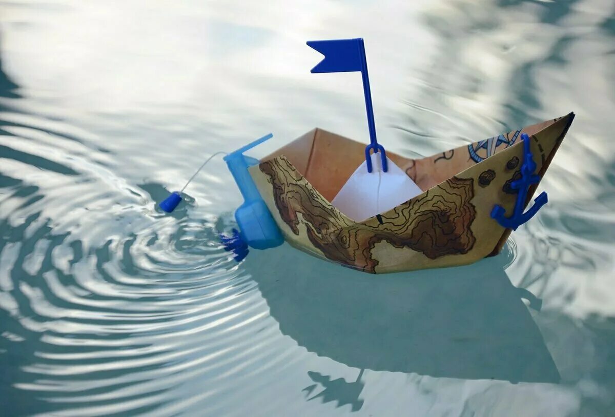 Бумажный кораблик. Бумажный кораблик в ручейке. Кораблик плывет.