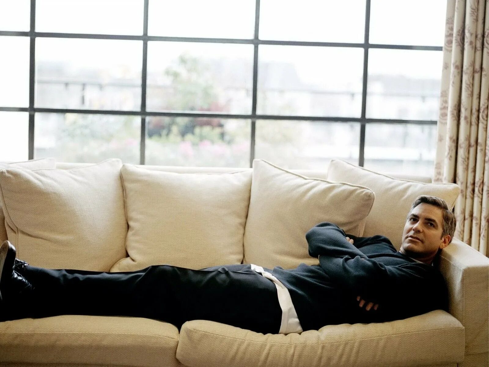 Сколько лет дивану. Джордж Клуни лежит на диване. Мужчина на диване. Парень лежит на диване. Мужская фотосессия на диване.