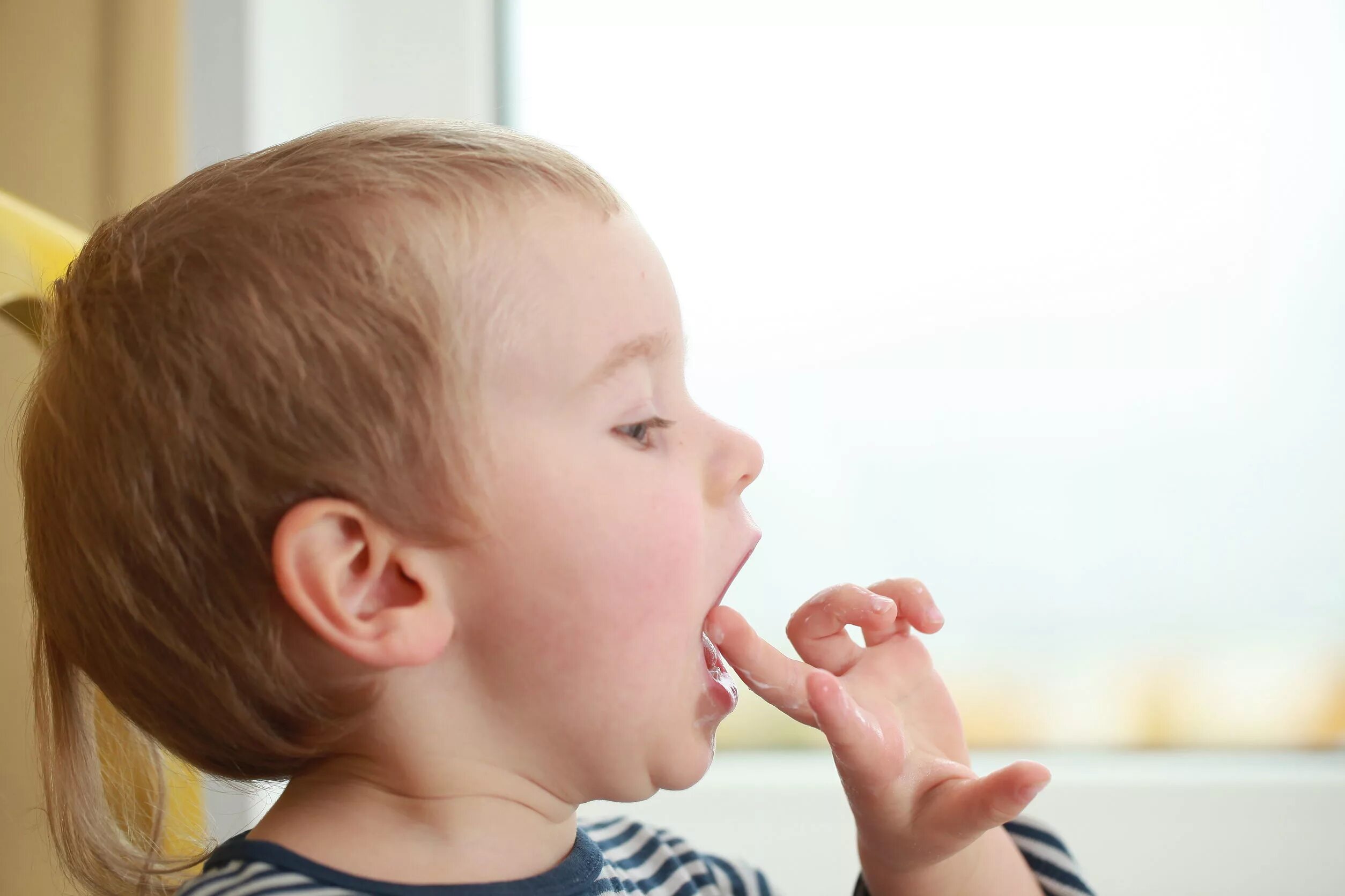 Дизартрия языка у детей. Ребенок облизывает пальцы. Маленькие девочки с леденцом во рту. Ребенок облизывает рот. Сосание пальца у детей.