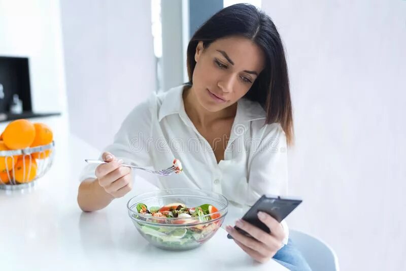 Человек ест салат. Девушка с телефоном во время обеда. Робот ест салат.