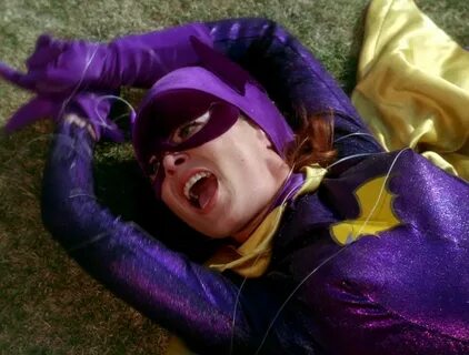 a woman dressed in purple and yellow laying on the ground 