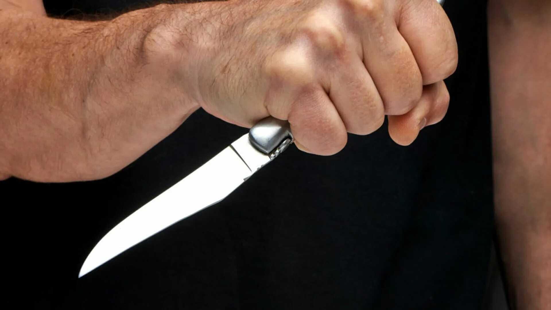 Кухонный нож в мужской руке за спиной.