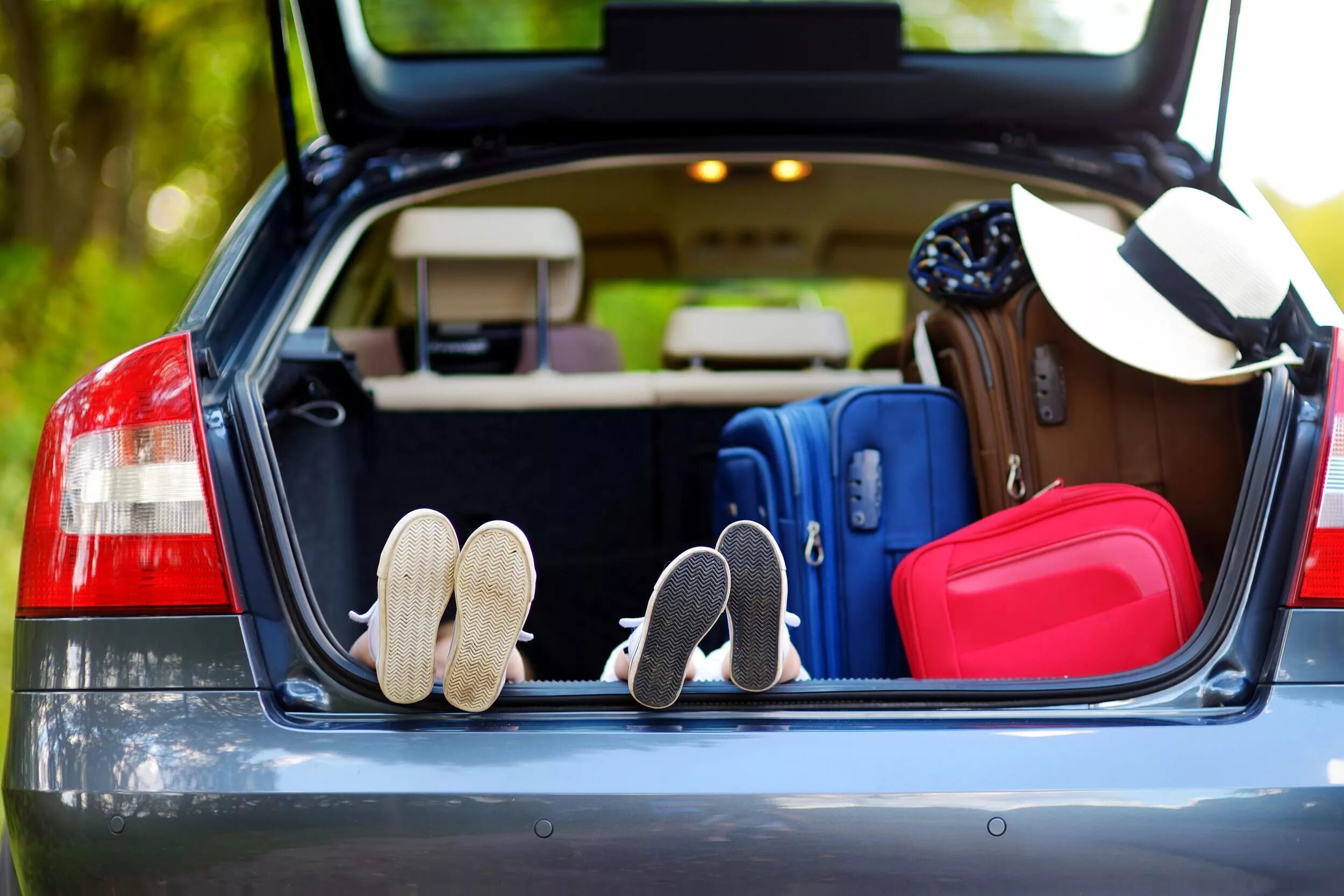 Holiday car rental. Путешествие на автомобиле. Семья в кабриолете. Девушка в кабриолете со спины. Вещи в багажнике.