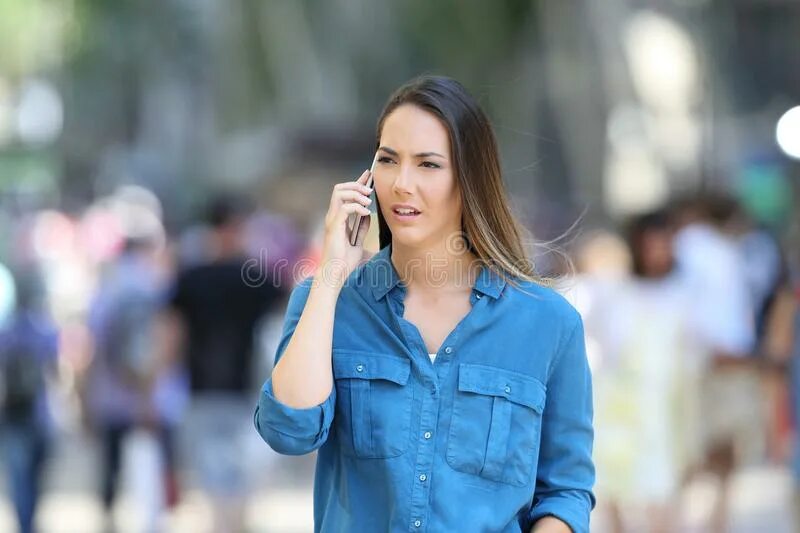 Телефон погулять. Женщина по телефону на улице. Женщина разговаривает на телефоне на улице. Женщина серьезная на улице. Девушка в синем говорит по телефону.