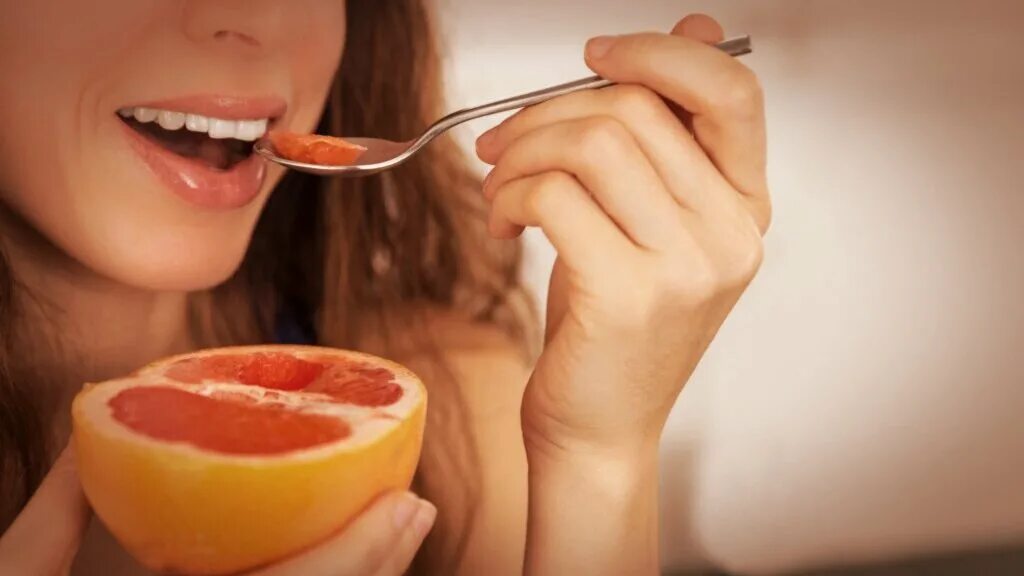 Горечь во рту после жирной пищи. Девушка ест грейпфрут. Девушка ест фрукты. Полезная пища для зубов. Человек ест фрукты.