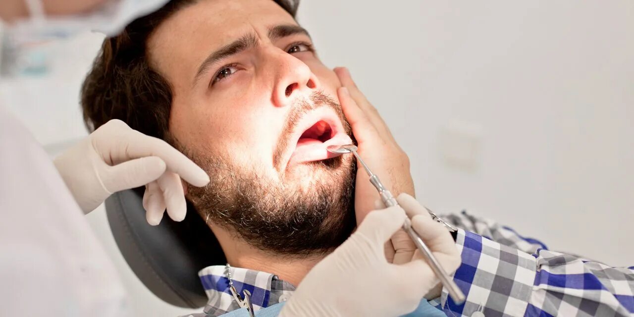 Диагноз боли в зубе. Парень у стоматолога. Болит зуб. Стоматолог мужчина.