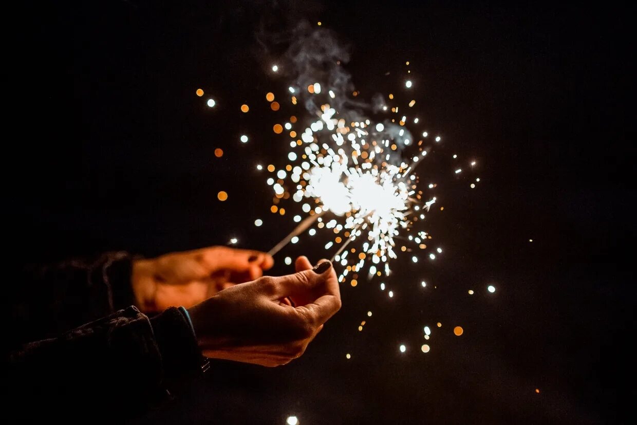 Догорающий бенгальский огонь в женской руке. Два бенгальских огня. Бенгальский огонь в руке. Бенгальские огни. Бенгальские огни.