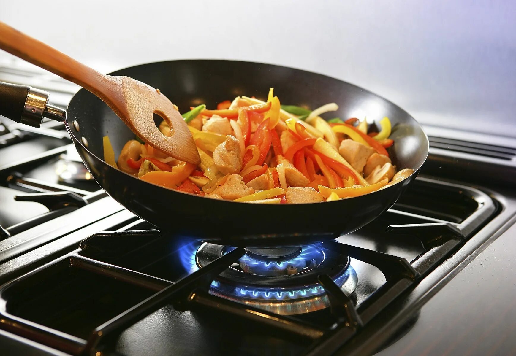 Газовая плита вок (Wok). Сковородка на огне. Приготовление пищи на огне. Сковородка с едой на плите. Wok плита газовая